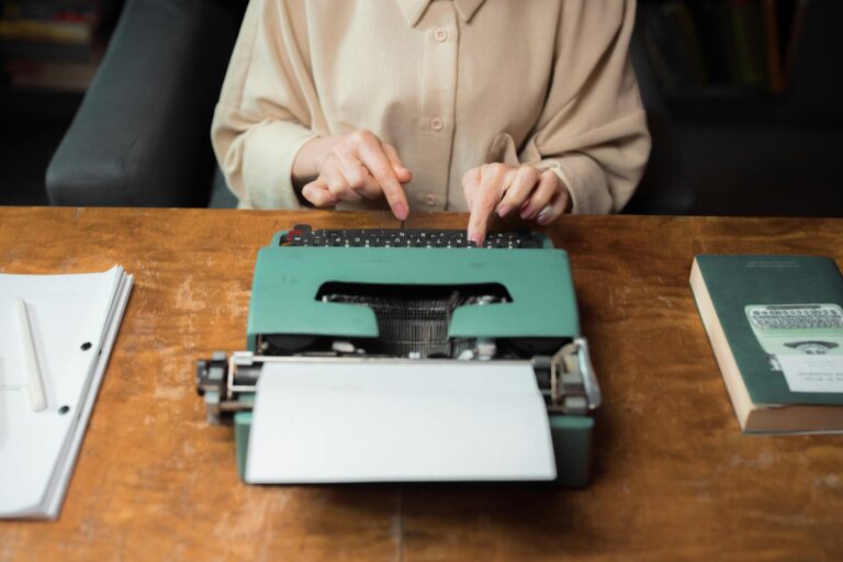 A person typing on a classic typewriter in a cozy office environment, surrounded by papers and books.